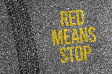 Asfalt zemin üzerinde sarı metin Red Means Stop ile tekerlek izi. Trafik yasası ve yol güvenliği farkındalığı kavramı.