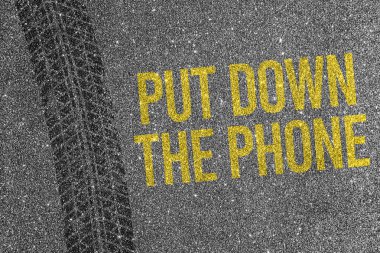 Asfalt zeminde sarı metinli lastik izi. Telefonu bırak. Yol güvenliği ve dikkati dağılmış sürüş konsepti.