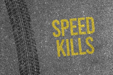 Asfalt zemin üzerinde sarı metin Speed Kills ile lastik izi. Yol güvenliği ve trafik tehlikesi kavramı.