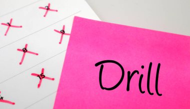Kırmızı tarihli takvimde Drill metni olan pembe yapışkan bir not. Güvenlik eğitimi, askeri tatbikat ve tekrarlanan beceri pratiği kavramı.