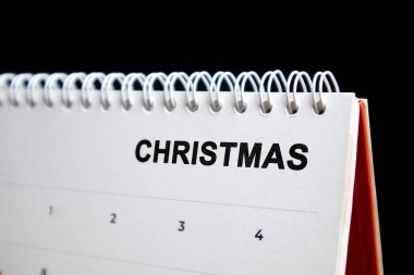 Noel için minimalist beyaz spiral takvim koyu arkaplan üzerine koyu siyah metin.