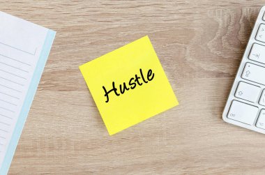 Sarı yapışkan bir nota, beyaz bir bilgisayar klavyesi ve bir not defterinin yanındaki açık ahşap ofis masasına elle yazılmış metni bastır.