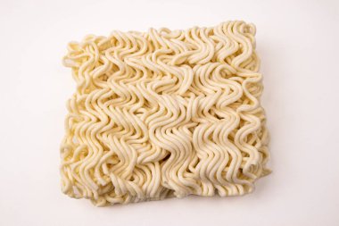 Düz beyaz arka planda izole edilmiş dalgalı desenli kuru, pişmemiş hazır eriştelerin kare görüntüsü.