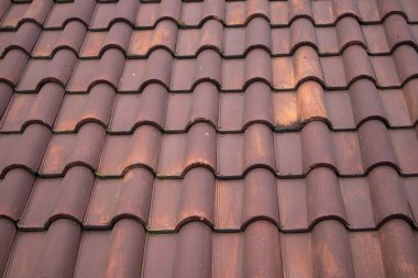 Bir evin üzerindeki eskimiş kahverengi kil kil çatı kiremitlerinin ayrıntılı deseni.