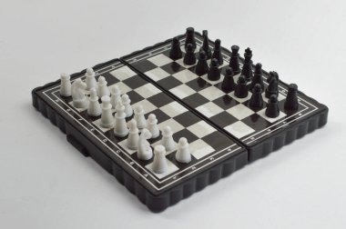 Karşıt taşların oynamaya, stratejiyi, rekabeti, eleştirel düşünmeyi ve klasik masa oyunu kavramlarını temsil etmeye hazır olduğu taşınabilir bir satranç tahtasının açılı görünümü.