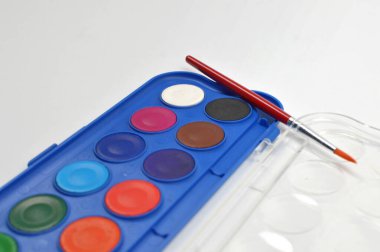 Portatif suluboya paleti parlak dairesel renkler ve fırça, resim, sanat pratiği, yaratıcılık ve sanatsal faaliyetler için ideal temiz bir stüdyo ortamında.