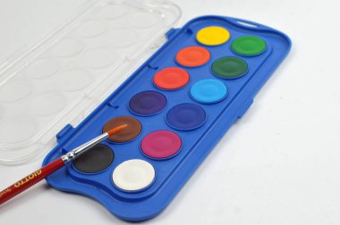 Açık suluboya palet canlı yuvarlak renkler ve fırça, sanat, resim pratiği ve yaratıcı kavramlar için temiz bir yüzey üzerine düzenlenmiş.