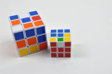 Temiz bir arkaplana yerleştirilmiş iki renkli bulmaca küpü, mantık oyunları, beyin eğitimi, problem çözme ve eğitici oyuncakları sembolize ediyor..