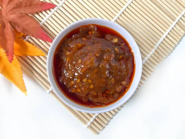 Sambal Goreng, bambu hasırında servis edilen kırmızı acı biber sosu. Zengin dokuyu, canlı rengi ve geleneksel Endonezya çeşni tarzını gösteriyor. Üst Görünüm.