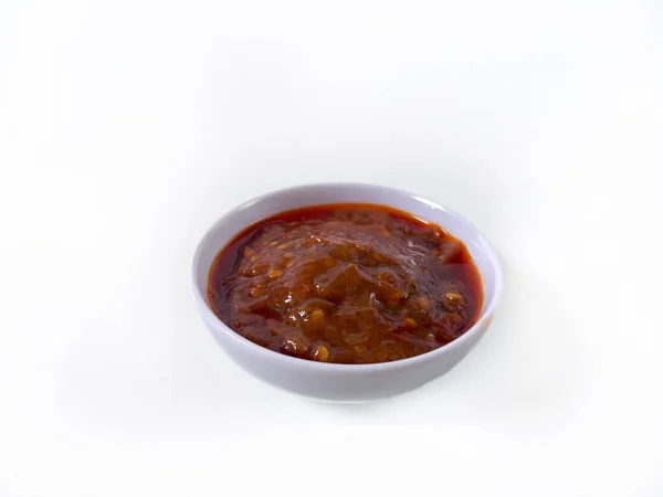 Sambal Goreng, beyaz kasede servis edilen kırmızı acı biber sosu. Zengin dokuyu, canlı rengi ve geleneksel Endonezya çeşni tarzını gösteriyor. izole.