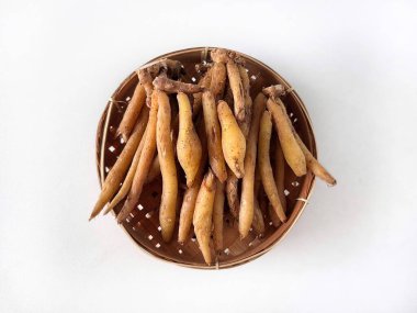 Temu Kunci veya Parmak Kökü (Boesenbergia rotunda) ya da beyaz arka planda izole edilmiş Bambu Tepsisi üzerindeki Çince anahtarlar. Aşçılıkta, geleneksel tıpta ve Asya mutfağında kullanılan romatik bitkisel rizom.