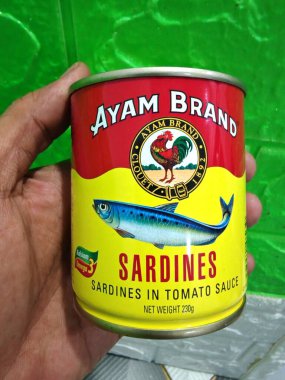 29 Ekim 2025 'te Malezya, Terengganu' da çekilmiş, domates soslu bir kutu Ayam Brand sardalyasını tutan bir el.