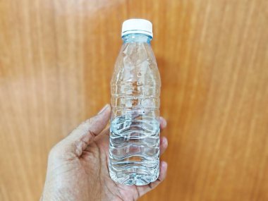 İnsan eli temiz bir plastik su şişesini tutuyor, günlük su kaybını, sağlıklı yaşam tarzını, ferahlığı ve temiz içme suyu tüketimini temsil ediyor.