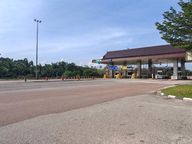 Terengganu, Malezya - 19 Ocak 2026: Yeşilliklerle çevrili birçok şeritli, ödeme işaretli ve geleneksel çatı tasarımlı gişeler