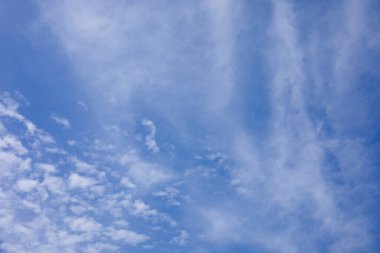 Işıl ışıl mavi bir gökyüzü kısmen kalın dokulu beyaz bulutlarla kaplı, açık bir açıklıkla gökyüzünün genişliğini ortaya çıkarıyor..