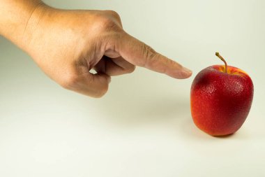 Bir el, temiz beyaz bir arkaplanda izole edilmiş tek ve canlı bir elmayı işaret ediyor. Kırmızı renkli ve sarı renkli meyveler, sağlık, seçim ve taze yemeği simgeler. Pazarlama için ideal.