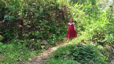 Çamurlu bir yolda, yemyeşil bir tropikal ormanda yalınayak yürüyen tatlı bir kız. Doğayı keşfeden ve tarlaya ya ya da çiftliğe giden mutlu bir çocuk. Çocukluk macerası ve kırsal yaşam kavramı.