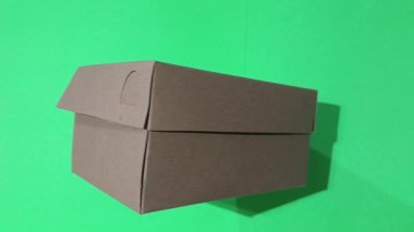 Yeşil ekran (kroma anahtarı) arka planında izole edilmiş kahverengi karton kutu veya teslimat paketi. Nakliye, ambalaj veya e-ticaret kavramı.