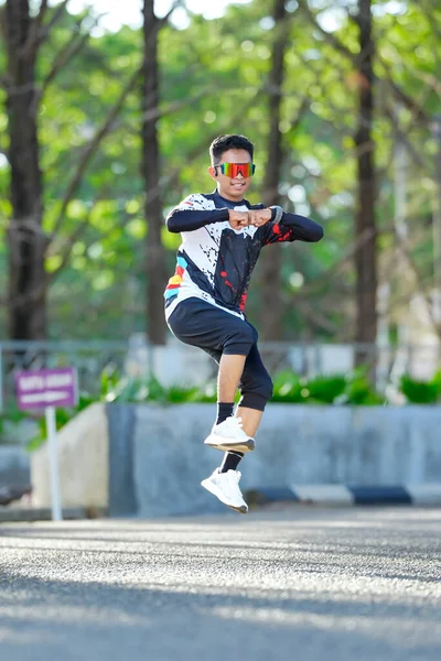 Genç adam havada zıplarken açık havada hareketli bir dans gösterisi yapıyor.