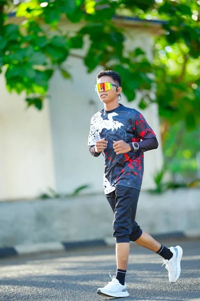 Aktif genç adam dışarıda koşuyor. Spor kıyafetler giyiyor.