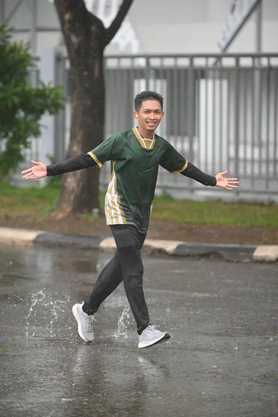 Genç bir adam neşeyle yürür yağmurda