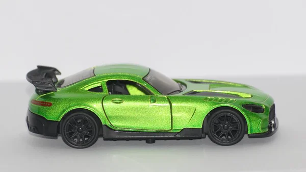Beyaz arka planda siyah tekerlekleri olan yeşil metalik bir spor araba.