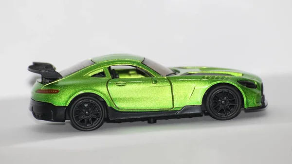 Beyaz arka planda siyah tekerlekleri olan yeşil metalik bir spor araba.