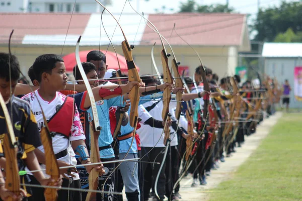 Banda Aceh, Endonezya - 8 Kasım 2025: Bir grup genç okçu açık hava okçuluğu sırasında ahşap yaylarını mükemmel bir şekilde hizalamaya çalışıyor