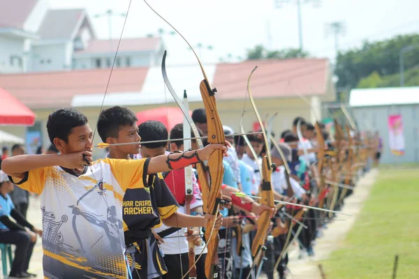 Banda Aceh, Endonezya - 8 Kasım 2025: Bir grup genç okçu açık hava okçuluğu sırasında ahşap yaylarını mükemmel bir şekilde hizalamaya çalışıyor