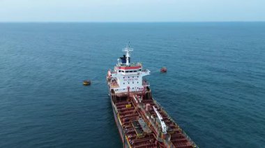 Açık denizde yelken açan büyük bir ticari kargo gemisinin hava görüntüsü.
