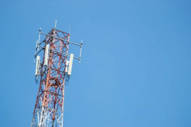 Telekomünikasyon kulesi açık mavi gökyüzüne karşı duran birden fazla anten ve vericiye sahip.