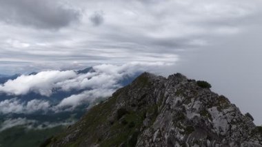 Kayalık bir dağ sırtı üzerinde geriye doğru uçan görkemli hava manzarası, altta dönen bulutlarla, yavaş yavaş yeşil çayırlar ve küçük bir göl olan Dachstein, Avusturya 'da nefes kesen bir alp vadisini ortaya çıkarıyor.