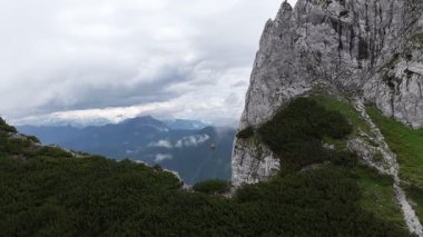 Muhteşem bir dağ sırasındaki yüksek bir uçurumdan atlayan heyecan arayan bir üssün havadan görünüşü, aşağıdaki vadiye paraşütle atlıyor dramatik zirveler ve yemyeşil ormanlarla çevrili.