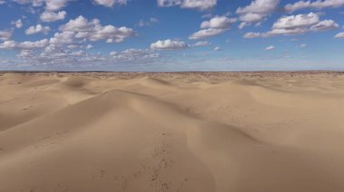 İnsansız hava araçları güzel mavi bir gökyüzünün altında sonsuz bir kum tepecikleri üzerinde uçarak huzurlu ve görkemli bir doğal manzara yaratıyor. Mangystau, Kazakistan.
