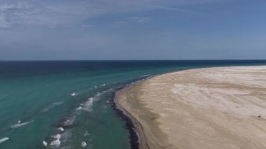 Uçsuz bucaksız, kumlu bir çöl manzarasıyla Hazar denizinin canlı turkuaz dalgaları arasındaki çarpıcı zıtlığı gösteren yüksek hava manzarası güzel ve sakin bir sahil manzarası yaratıyor, Mangystau, Kazakistan