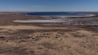Yüksek irtifada insansız hava aracı geriye doğru uçuyor. Terk edilmiş bir hayalet kasaba yerleşkesini ve geniş, tuzlu bir Aral denizini güneşli bir günde açık mavi bir gökyüzünün altında kurak ve kurak bir çöl arazisinde ortaya çıkarıyor.