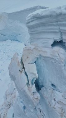 Bunaltıcı kutup manzarası, derin mavi çatlaklarıyla görkemli bir buzulu, donmuş yabanın sert güzelliğini ve katıksız ölçeğini ve iklim değişikliğinin etkilerini yansıtıyor.