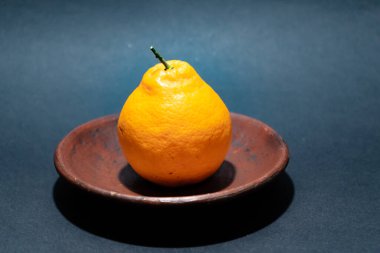 Tahta tabakta taze portakal meyvesi, siyah zemin üzerinde izole edilmiş Dekopon portakalı ya da iş yolu üzerinde sumo mandalina..