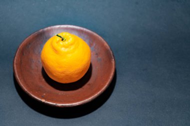 Tahta tabakta taze portakal meyvesi, siyah zemin üzerinde izole edilmiş Dekopon portakalı ya da iş yolu üzerinde sumo mandalina..