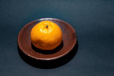 Tahta tabakta taze portakal meyvesi, siyah zemin üzerinde izole edilmiş Dekopon portakalı ya da iş yolu üzerinde sumo mandalina..