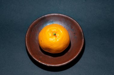 Tahta tabakta taze portakal meyvesi, siyah zemin üzerinde izole edilmiş Dekopon portakalı ya da iş yolu üzerinde sumo mandalina..