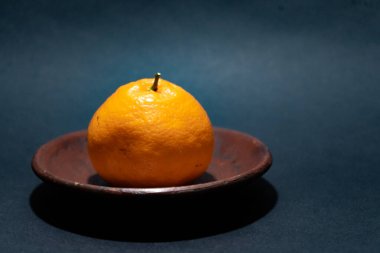 Tahta tabakta taze portakal meyvesi, siyah zemin üzerinde izole edilmiş Dekopon portakalı ya da iş yolu üzerinde sumo mandalina..