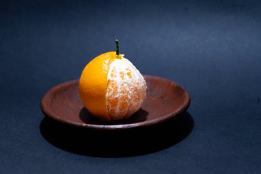 Tahta tabakta taze portakal meyvesi, siyah zemin üzerinde izole edilmiş Dekopon portakalı ya da iş yolu üzerinde sumo mandalina..