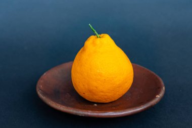 Tahta tabakta taze portakal meyvesi, siyah zemin üzerinde izole edilmiş Dekopon portakalı ya da iş yolu üzerinde sumo mandalina..