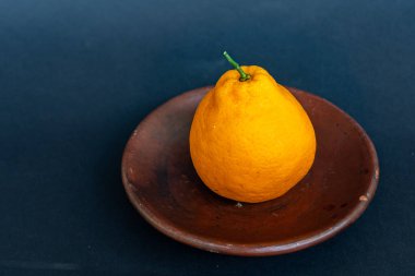 Tahta tabakta taze portakal meyvesi, siyah zemin üzerinde izole edilmiş Dekopon portakalı ya da iş yolu üzerinde sumo mandalina..