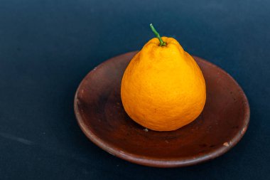 Tahta tabakta taze portakal meyvesi, siyah zemin üzerinde izole edilmiş Dekopon portakalı ya da iş yolu üzerinde sumo mandalina..