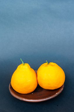 Tahta tabakta taze portakal meyvesi, siyah zemin üzerinde izole edilmiş Dekopon portakalı ya da iş yolu üzerinde sumo mandalina..