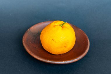 Tahta tabakta taze portakal meyvesi, siyah zemin üzerinde izole edilmiş Dekopon portakalı ya da iş yolu üzerinde sumo mandalina..