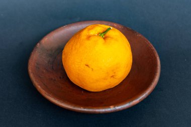 Tahta tabakta taze portakal meyvesi, siyah zemin üzerinde izole edilmiş Dekopon portakalı ya da iş yolu üzerinde sumo mandalina..