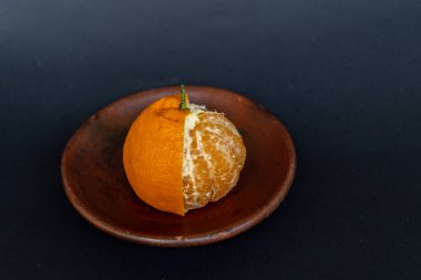 Tahta tabakta taze portakal meyvesi, siyah zemin üzerinde izole edilmiş Dekopon portakalı ya da iş yolu üzerinde sumo mandalina..